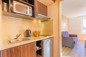 a small kitchen with a sink and a microwave at Appart'City Classic Genève - Gaillard in Gaillard