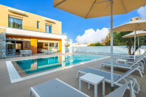a swimming pool with chairs and an umbrella next to a house at Ialyssos Charme Villa in Ialyssos