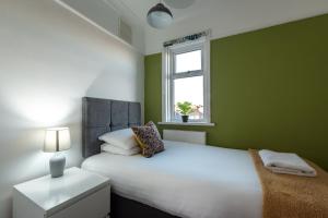 Dormitorio verde con cama blanca y ventana en Comfortable and convenient stay 3 bed house, en Southampton