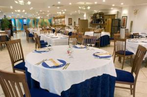 een eetkamer met witte tafels en blauwe stoelen bij Baraka Apartments in Scoglitti