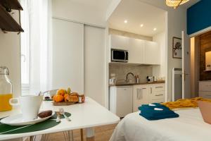 una cucina con armadi bianchi e un tavolo con un cesto di frutta di VilleneuveCityStay Jungle a Villeneuve-sur-Lot