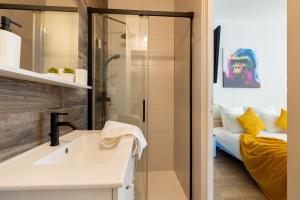 un bagno con lavandino e doccia e un letto di VilleneuveCityStay Jungle a Villeneuve-sur-Lot