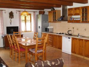 a kitchen with a wooden table and chairs and a table and a kitchen at Chalupa Les Království in Souvrať