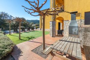 un árbol frente a una casa con un banco en Villa la Roca en Sant Antoni de Calonge