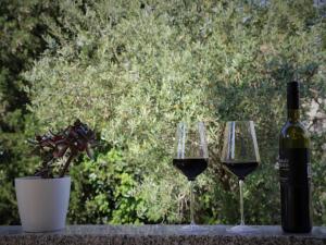three wine glasses and a bottle of wine on a table at Apartment Marina in Punat