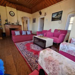 a living room with pink couches and a table at Zeus Bungalow in Kotagiri