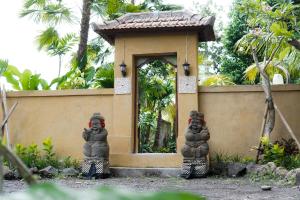 two statues standing in front of a small building at Sentana Villa Ubud in Ubud