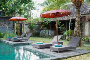 a group of chairs with umbrellas next to a pool at Sentana Villa Ubud in Ubud