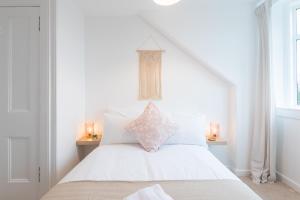 una camera bianca con un letto bianco e un cuscino rosa di Glengate - Traditional home in Kirriemuir a Kirriemuir