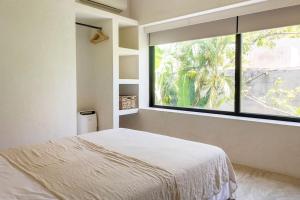 ein Schlafzimmer mit einem Bett und einem großen Fenster in der Unterkunft Casa Areca, Awarded Architectural Villa located in a secured gated community, with Concierge services in Tulum