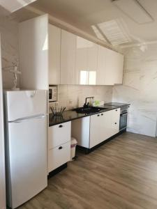 a kitchen with white cabinets and a refrigerator at Casa do Paço in Almeirim