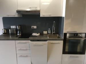 a kitchen with white cabinets and a stove top oven at charmant studio vue mer in Wimereux