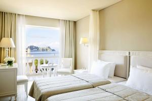 ein Hotelzimmer mit einem Bett und einem großen Fenster in der Unterkunft Mon Repos Palace - Adults Only in Korfu-Stadt
