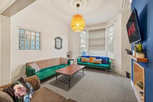 a living room with a green couch and a table at Large Central Cardiff House - Games Room - Sleeps 12 in Cardiff