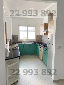 a kitchen with green cabinets and a window at S2 in second position beach Dar Allouche Kelibia in Hennchir Ksar Rhaleb