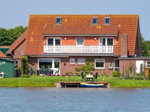 een huis op het water met een boot ervoor bij Haus Shalom in Neuharlingersiel