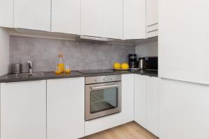a kitchen with white cabinets and an oven at Nowa Grobla Estate Apartment near Starówka by Renters in Gdańsk
