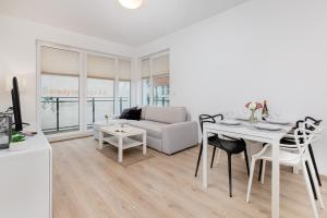 een witte woonkamer met een tafel en een bank bij Nowa Grobla Estate Apartment near Starówka by Renters in Gdańsk