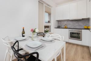 a white kitchen with a white table and chairs at Nowa Grobla Estate Apartment near Starówka by Renters in Gdańsk