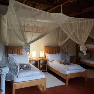a bedroom with two beds and a fan at Ng'ona Lodge in Maganga