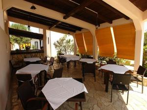 ein Restaurant mit Tischen und Stühlen mit weißen Tischen in der Unterkunft Pansion Jurko in Pag
