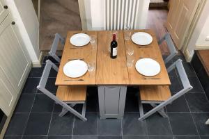 a wooden table with white plates and a bottle of wine at Grade II Townhouse, Ledbury in Ledbury