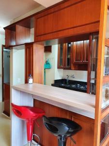 a kitchen with red stools and a counter with a sink at Flat Wall Street in Caxias do Sul