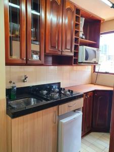 a kitchen with wooden cabinets and a sink and a stove at Flat Wall Street in Caxias do Sul