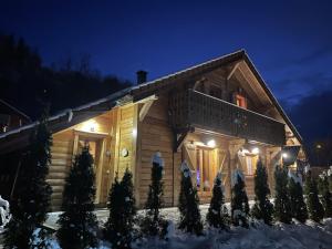 una cabaña de madera en la nieve por la noche en ⁂⁂ LE NID DE PIERRE & JULIE [CLEDICIHOME] 2 pas du centre ville / SPA & TERASSE AMENAGEE ⁂⁂ en La Bresse