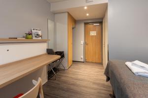 a room with a bed and a desk and a door at Hotel Linnasm&auml;ki in Turku
