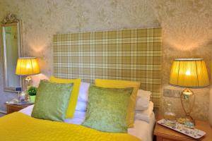 a bedroom with a bed with yellow pillows and two lamps at Bryn Tyrch Rooms in Capel-Curig