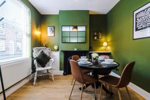 a dining room with green walls and a table and chairs at Cornwall House in Chester