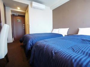 two beds in a hotel room with blue sheets at HOTEL LiVEMAX Yokohama Motomachi Ekimae in Yokohama