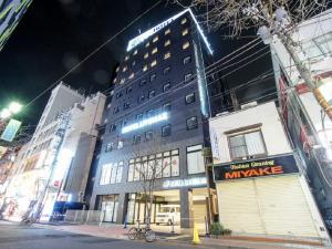 un gran edificio en una calle de la ciudad por la noche en HOTEL LiVEMAX Yokohama Motomachi Ekimae en Yokohama