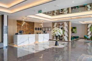 DAMAC Hills 2 Hotel, an Edge by Rotana Hotel في دبي: لوبي فيه مكتب استقبال وزهور في مزهرية