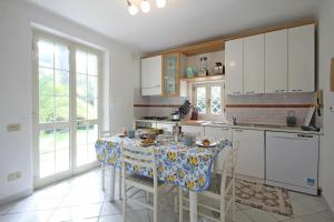 uma cozinha com uma mesa com cadeiras e uma cozinha com armários brancos em Villa Poveromo em Massa