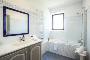 La salle de bains est pourvue d'un lavabo, d'une baignoire et d'un miroir. dans l'établissement Le Clos Du Buis, à Bonnieux