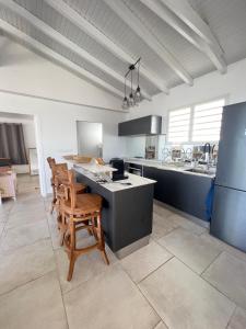 a kitchen with wooden chairs and a counter in a room at Villa Amaryllis luxueuse,piscine,vue mer,plage in Sainte-Luce