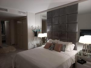 een slaapkamer met een groot wit bed met 2 lampen bij PENTHOUSE and ENTERTAINMENT VENUE with AMAZING VIEWS in the Finca Cortesin complex in Casares