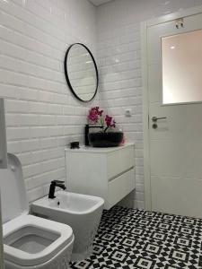 bagno bianco con servizi igienici e specchio di Casa Berlenga a Peniche