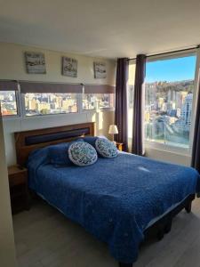 een slaapkamer met een blauw bed en een groot raam bij Hermoso departamento en Viña del Mar/Casino in Viña del Mar
