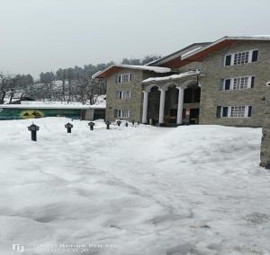 a snow covered parking lot in front of a building at Hotel Outlook in Pahalgām