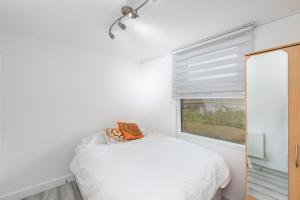 um quarto com uma cama branca e uma janela em Modern Central 2bed 2bath Stratford Apt em Londres