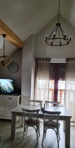 a dining room with a table and chairs and a tv at Apartamenty Homole Mansarda in Szczawnica