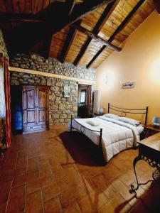 1 dormitorio con cama y pared de piedra en Agriturismo Le Grotte, en Nemi