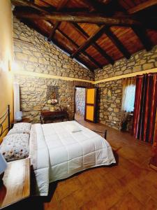 a bedroom with a large bed and a stone wall at Agriturismo Le Grotte in Nemi