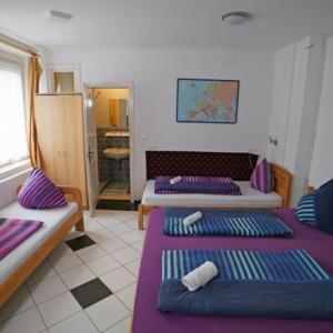 Cette chambre comprend 3 lits avec des draps violets. dans l'établissement Balaton Vendégház Fonyód, à Fonyód