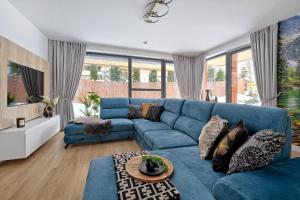 Sofá azul en la sala de estar con ventanas en Apartament Morskie Oko Odkryj Zakopane, en Zakopane