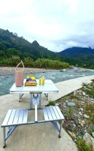 a picnic table and bench next to a river at Rainbow Lodge Tambatuon in Kota Belud