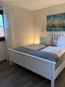 a white bed in a bedroom with a painting on the wall at Räuberlager 15 in Dammbach